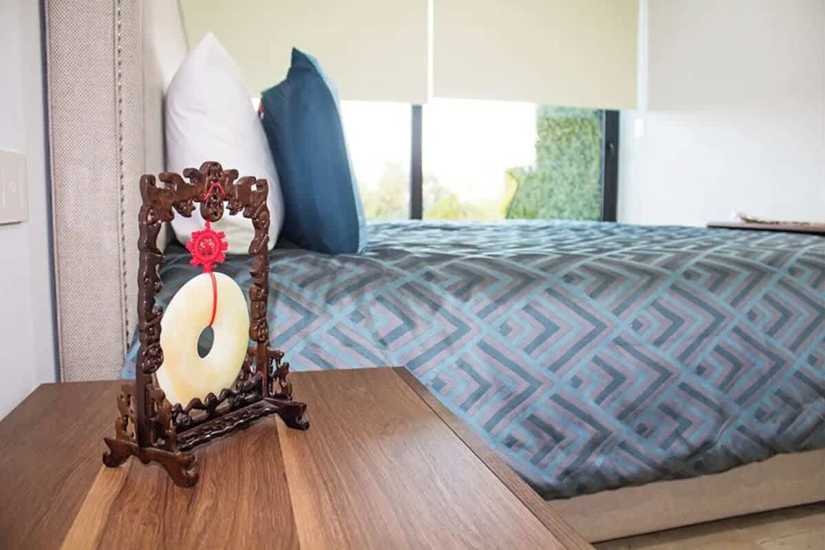 A bed with a patterned bedspread, a decorative wooden frame with a red ornament, and a pillow on the bed.