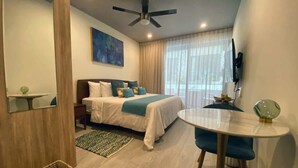 A hotel room with a bed, a round table, a chair, a ceiling fan, and a TV mounted on the wall. - Rooftop Pool Studio 200m from Coco Beach (Playa del Carmen)