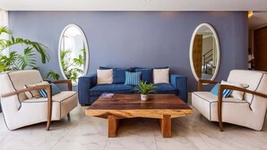 A modern living room with a blue sofa, two armchairs, a wooden coffee table, and large mirrors on the walls. - Rooftop Pool Studio 200m from Coco Beach (Playa del Carmen)
