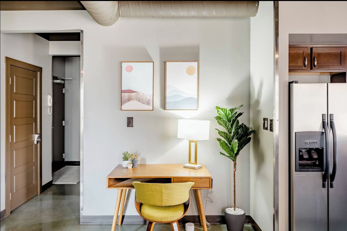 A modern kitchen with a refrigerator, a water dispenser, and a wooden dining table with a chair.