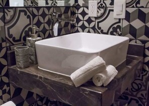 A bathroom with a white sink, a marble countertop, and patterned tiles. - Beachside Studio & Jacuzzi Bliss (Playa del Carmen)