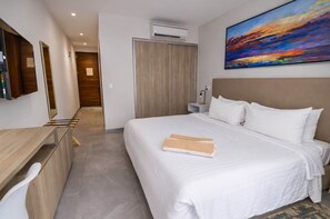 Een hotelkamer met een bed, een bureau, een stoel, een schilderij en een airconditioner.