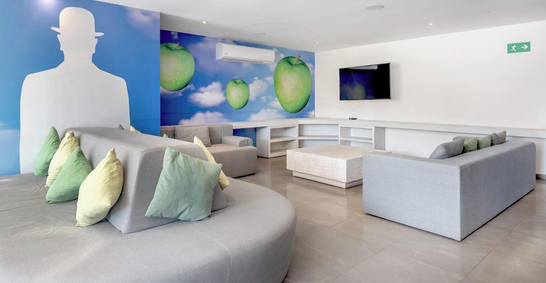 A modern reception area with a large wall mural, a flat-screen TV, and a seating arrangement.