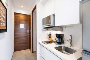 Een moderne keuken met een magnetron, koffiezetapparaat en een roestvrijstalen spoelbak.