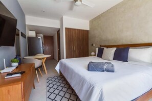 Ein Hotelzimmer mit einem Bett, einem Schreibtisch, einem Stuhl, einem Fernseher und einem Kleiderschrank.