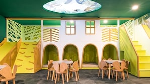Un espace de jeux pour enfants avec des murs d’escalade, des toboggans et des sièges en forme d’arche.