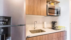 Une cuisine moderne équipée d’un four à micro-ondes encastré, d’un évier en acier inoxydable et d’une machine à café.