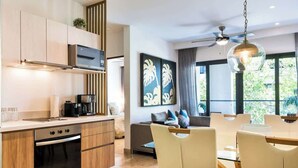 Een moderne keuken met inbouwapparatuur, een eethoek met tafel en stoelen, en een groot raam dat voor natuurlijk licht zorgt.