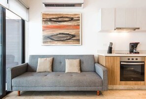 Eine moderne Küche mit einem grauen Sofa, einem Gemälde und einer Kaffeemaschine.