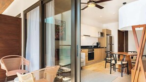 Un interior moderno con comedor, cocina y un piso de vidrio corredera que da a un balcón.