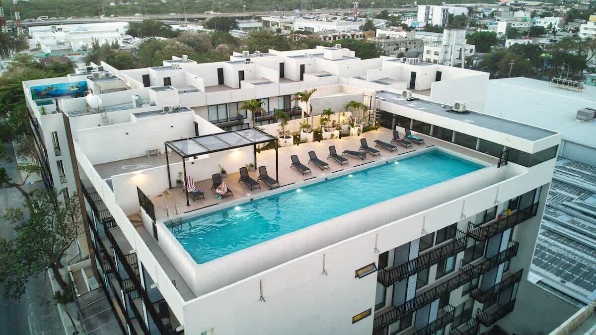 A rooftop pool with lounge chairs and a glass enclosure.