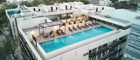 Une piscine sur le toit, dotée de chaises longues et protégée par une paroi en verre.
