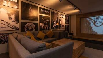 Un salon moderne doté d’un grand écran, de sièges confortables et d’affiches de films accrochées au mur.