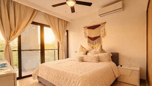 Een slaapkamer met een bed, nachtkastje, plafondventilator en uitzicht op de omgeving.
