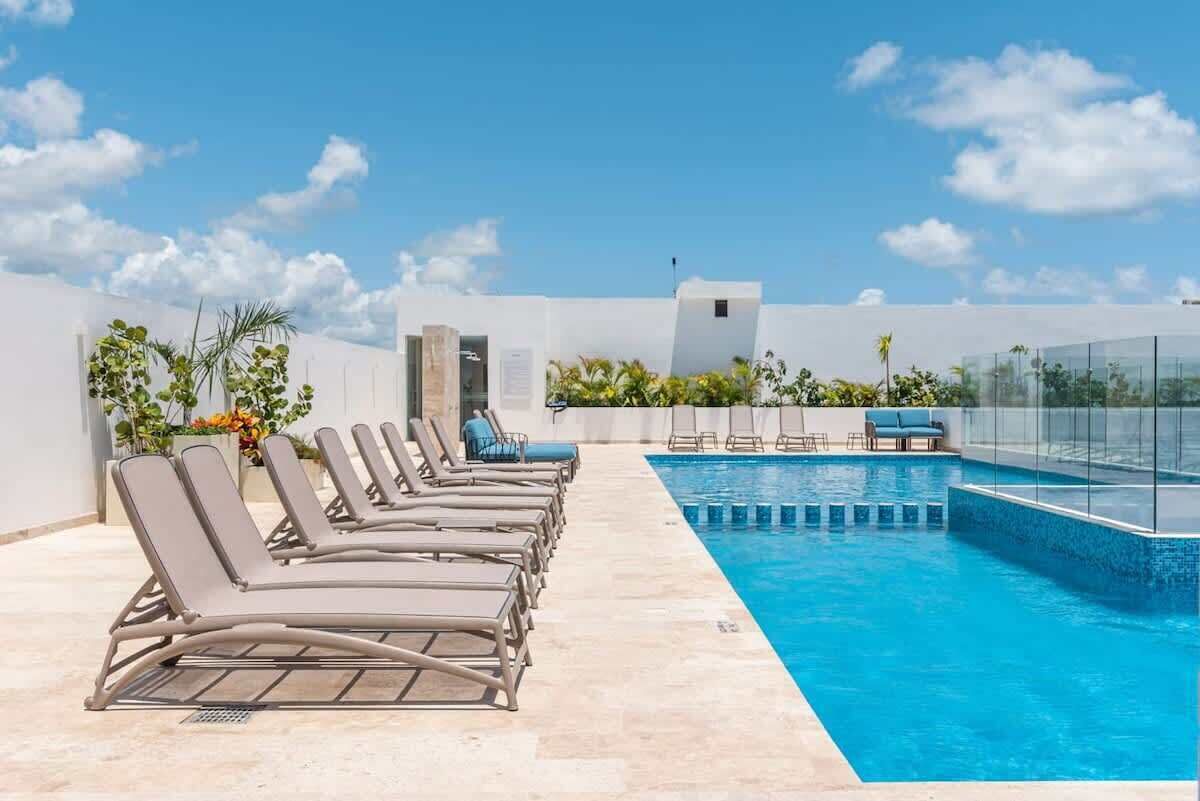 Zona junto a la piscina con tumbonas, una piscina y cielo despejado.