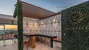 Eine Dachterrasse mit einem geometrischen Wanddesign, einer Holzpergola und Blick auf die Stadtlandschaft.