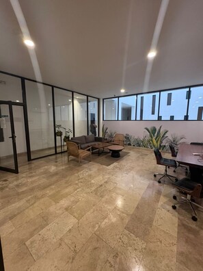 Una oficina amplia con una gran mesa de reuniones, asientos cómodos y amplios ventanales que ofrecen vistas al exterior.