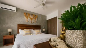 A modern bedroom with a large bed, a wooden nightstand, a bedside table, a ceiling fan, a wardrobe, and a decorative plant. - Studio w Rooftop Pool Near Beach & 5th Ave (Playa del Carmen)