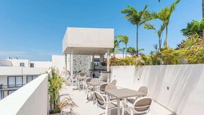 A rooftop terrace with outdoor seating and a view of the city. - Studio w Rooftop Pool Near Beach & 5th Ave (Playa del Carmen)