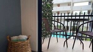 A balcony with wicker furniture and a view of a swimming pool. - Studio w Rooftop Pool Near Beach & 5th Ave (Playa del Carmen)
