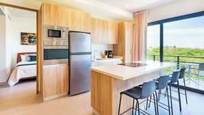Una cocina moderna con armarios de madera, un refrigerador de acero inoxidable y una isla grande con taburetes de bar.