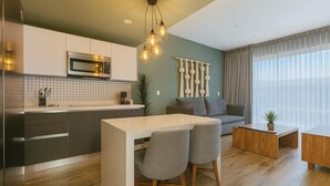 Uma cozinha moderna com uma ilha central, área de jantar com duas cadeiras, um sofá e uma mesa de centro.