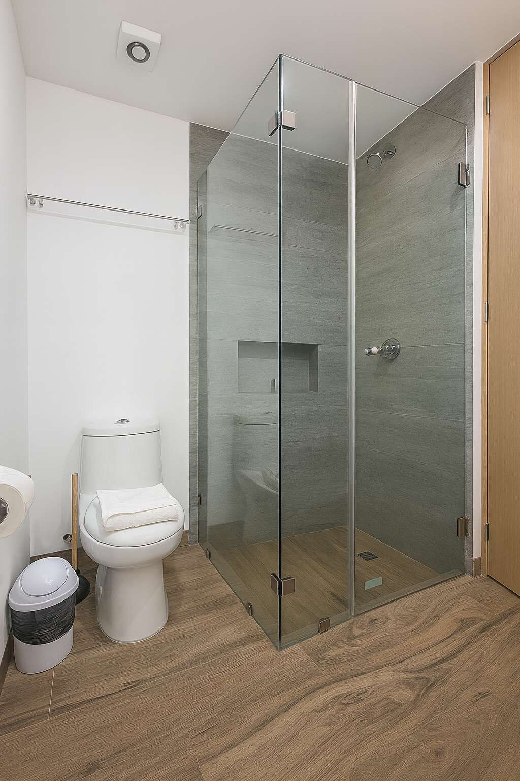 A modern bathroom with a glass-enclosed shower, a toilet, and a bidet.