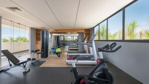 Academia moderna com esteiras, um banco e bolas de exercício.