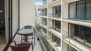 Um apartamento moderno com varanda, área de refeições com cadeiras e vista para o interior do edifício.