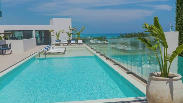 Ein moderner Poolbereich mit klarem, blauem Wasser, Liegestühlen und Blick auf den Ozean.