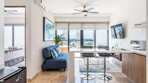 A modern hotel room with a balcony, a dining area, and a TV. - Rooftop Pool and Private Hot Tub with Ocean Views (Playa del Carmen)