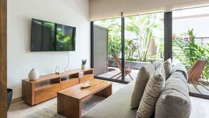 Una sala de estar moderna con un televisor de pantalla plana, mueble de madera para entretenimiento y un sofá con cojines estampados.