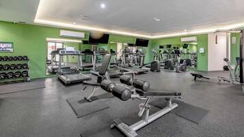 Una palestra con tapis roulant, macchinari per pesi e manubri.