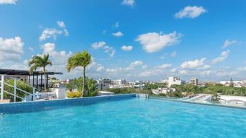 Una piscina sul tetto con acqua cristallina, circondata da palme e una vista sulla città.