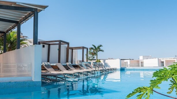 A pool area with lounge chairs and a covered seating area. - Modern Studio w Rooftop Pool Near Beach & Dining (Playa del Carmen)
