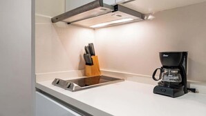 A kitchen with a built-in stove, a coffee maker, and a knife block. - Modern Studio w Rooftop Pool Near Beach & Dining (Playa del Carmen)