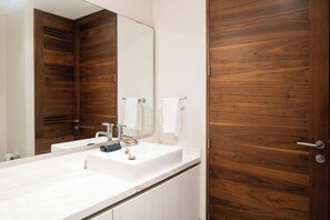 A modern bathroom with a white sink, a large mirror, and wooden doors. - Modern Studio w Rooftop Pool Near Beach & Dining (Playa del Carmen)