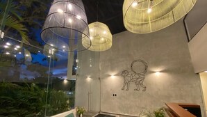 Un interior moderno con lámparas colgantes, un sofá verde, una recepción y un mural de un perro.