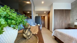 Una habitación de hotel moderna con una cama, una planta grande en maceta, una estatua dorada decorativa y vistas al pasillo.