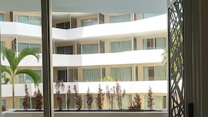 Ein Balkon mit Blick auf ein mehrstöckiges Gebäude, Holzboden und zwei Korbstühle.