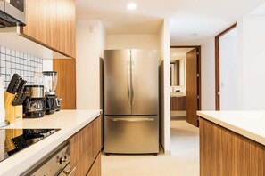 Eine moderne Küche mit einem Edelstahl-Kühlschrank, Holzschränken und einer weißen Arbeitsplatte.