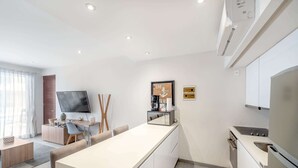 A modern kitchen with a central island, built-in appliances, and a flat-screen TV. - Rooftop Pool & Gym Near 5th Avenue Activities (Playa del Carmen)