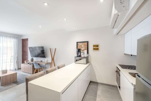 A modern kitchen with a central island, built-in appliances, and a flat-screen TV. - Rooftop Pool & Gym Near 5th Avenue Activities (Playa del Carmen)