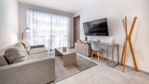 A modern living room with a sofa, coffee table, and a TV mounted on the wall. - Rooftop Pool & Gym Near 5th Avenue Activities (Playa del Carmen)