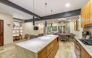 A modern kitchen with a large island, wooden cabinets, and a built-in stove. - 3BR Playacar Villa w Pool & Private Patio (Playa del Carmen)