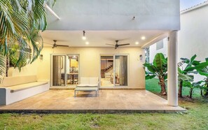 A covered patio area with a seating arrangement, a ceiling fan, and a staircase leading to an upper level. - Beautiful 3BD House in Playacar (Playa del Carmen)