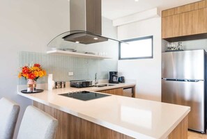 A modern kitchen with a central island, stainless steel appliances, and a tiled backsplash. - 1BR in top location w Ocean View (Playa del Carmen)