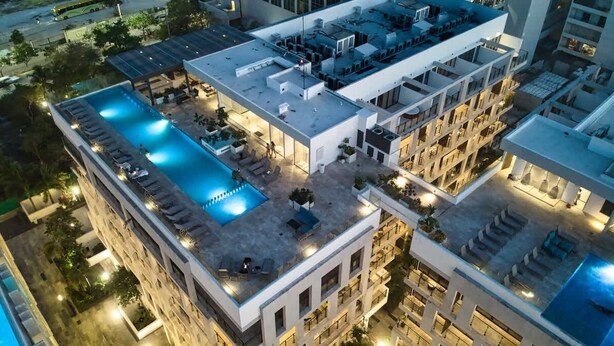 Un área de piscina en la azotea con sillones de descanso y un espacio de estar cubierto.