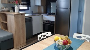 Une cuisine compacte dotée d’appareils électroménagers modernes, un coin repas avec une table et un petit espace salon.