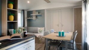 Une cuisine moderne avec un plan de travail en bois, une table à manger avec des chaises et un meuble de rangement intégré agrémenté d’objets décoratifs.